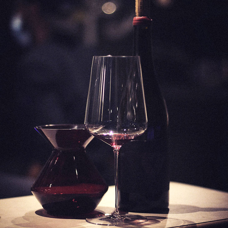 Photo d'un verre de vin rouge avec bouteille et caraphe arrière plan