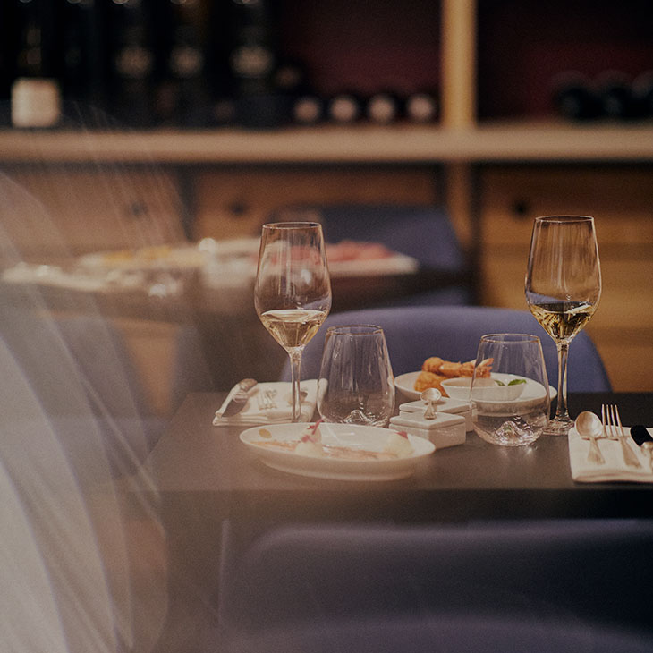 Photo d'une table pour deux de la salle du restaurant du 5 Wine Bar situé dans une cave sous le bar : 2 verres de vin doux et 2 assiettes avec menu gastronomique